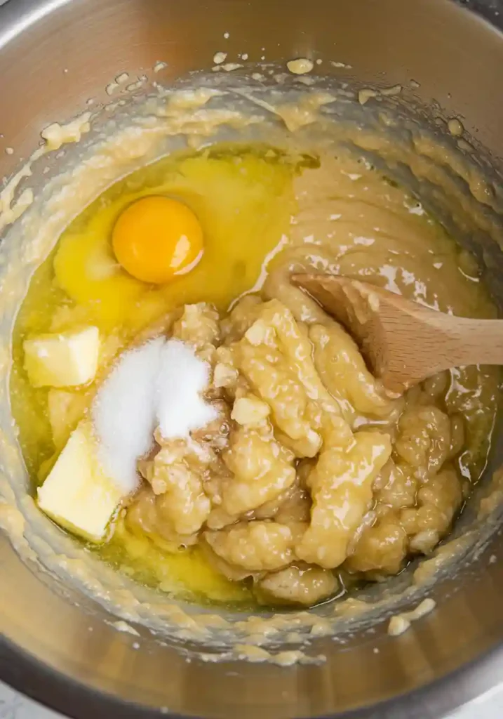 Mashed bananas, sugar, butter, and eggs in bowl