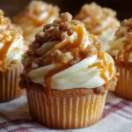Delicious apple pie cupcakes topped with swirled cinnamon buttercream frosting on a rustic wooden board