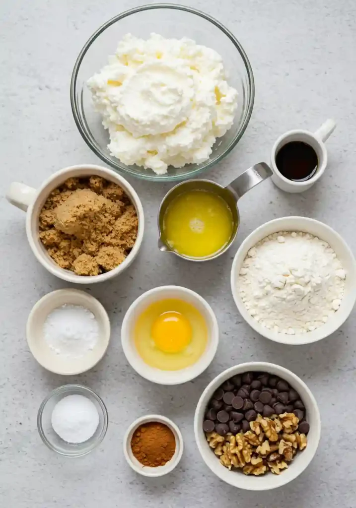 All ingredients for cottage cheese chocolate chip cookies laid out including cottage cheese, flour, chocolate chips, and spices