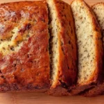 Sliced Greek yogurt banana bread on wooden cutting board showing moist texture and golden brown color