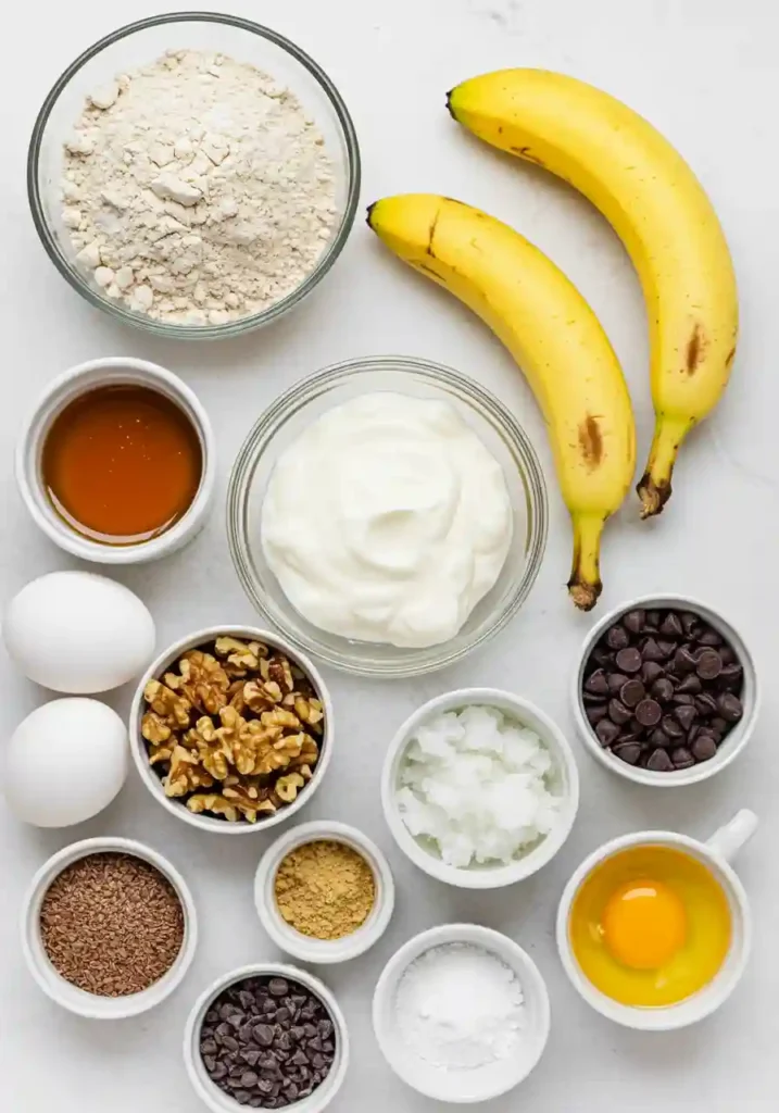 Greek yogurt banana bread ingredients including ripe bananas, Greek yogurt, flour, and spices arranged on white counter