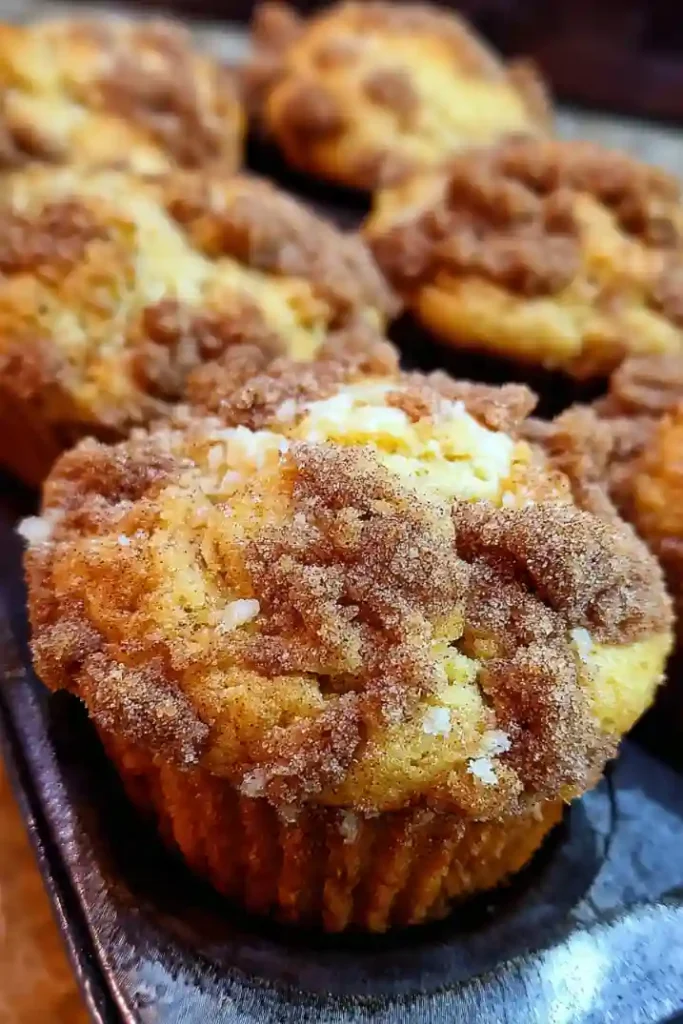 Muffin tin showing assembled coffee cake muffins with streusel layers before baking