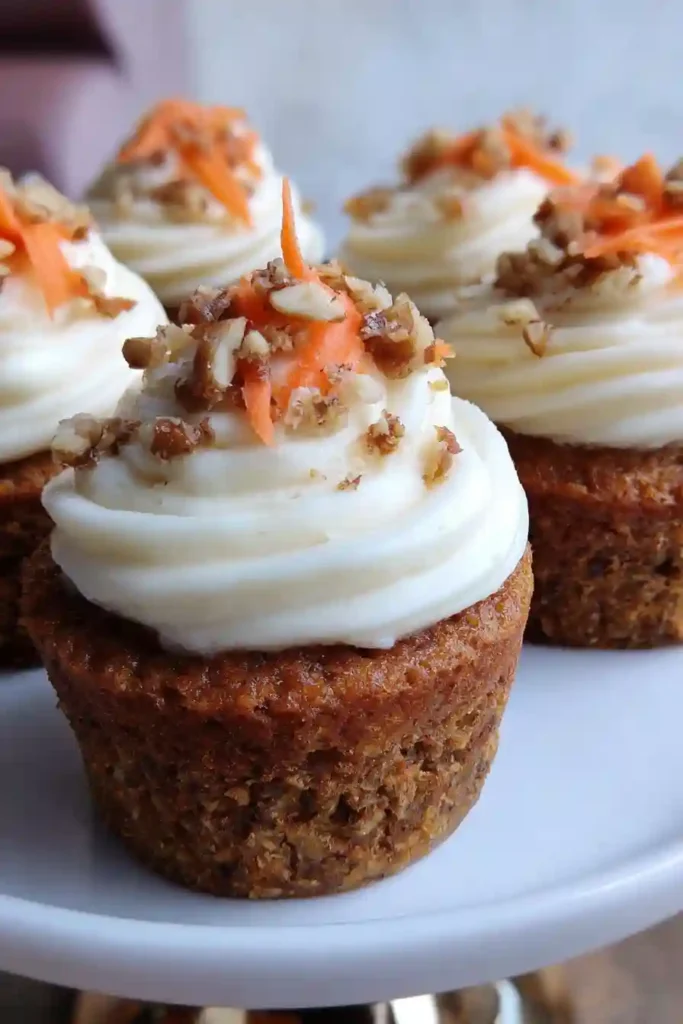 Electric mixer beating fluffy white cream cheese frosting in stainless steel bowl for carrot cupcakes