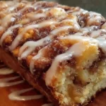 Sliced cinnamon swirl apple fritter bread on wooden cutting board with brown sugar glaze drizzled on top