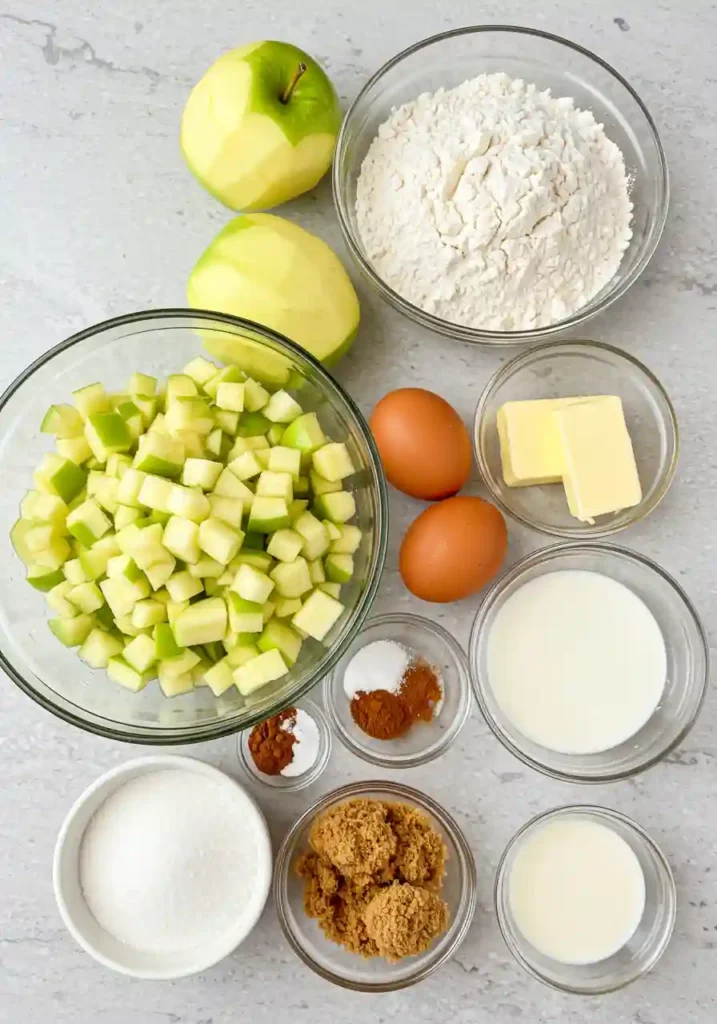 All ingredients for cinnamon swirl apple fritter bread arranged on counter including flour, apples, brown sugar, and spices