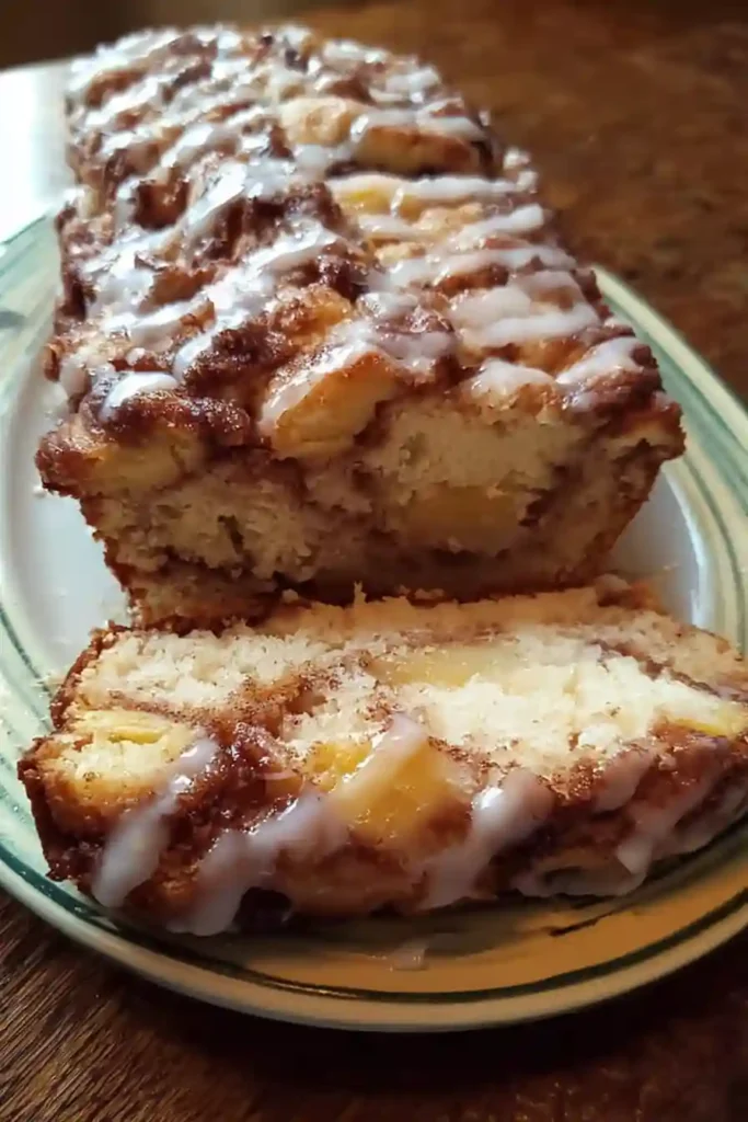 Brown sugar glaze being drizzled over cooled apple fritter bread loaf on cooling rack