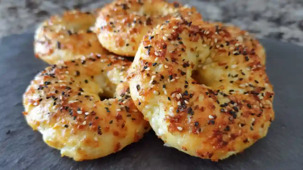 Four golden-brown cottage cheese bagels in air fryer basket, topped with everything seasoning, showing perfect texture and color