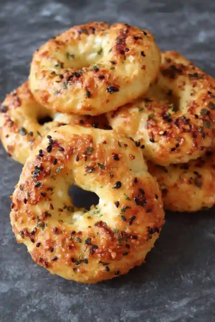 Hands shaping cottage cheese dough into bagel rings on floured surface, showing proper technique