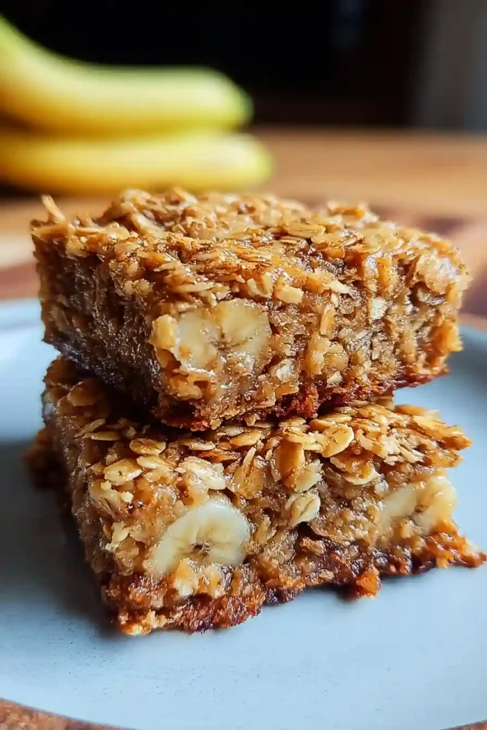 Slicing cooled banana oatmeal bars into individual squares on wooden cutting board