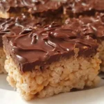 Stack of Chocolate Peanut Butter Rice Krispie Treats showing layers of chocolate topping and crispy marshmallow base