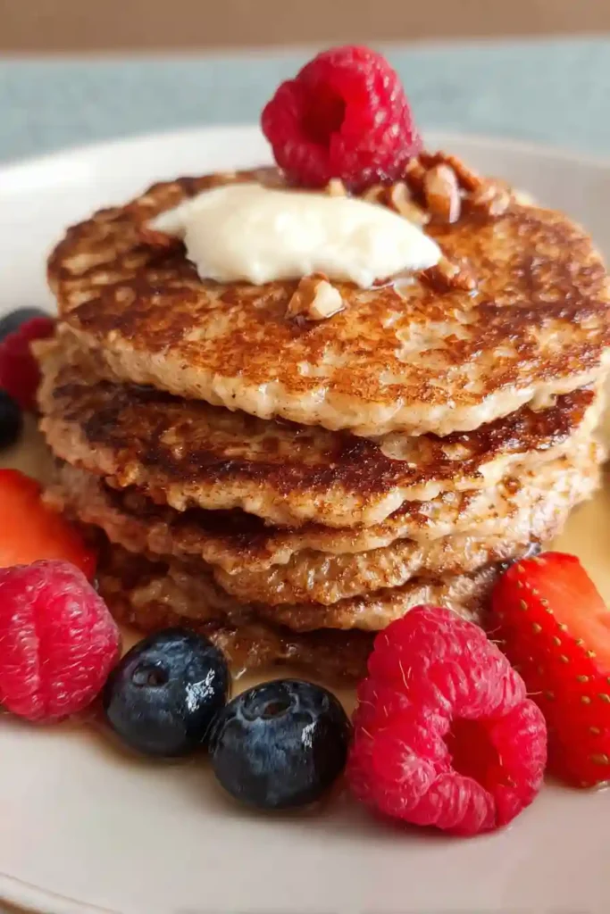 Golden-brown cottage cheese oatmeal pancake being flipped with spatula in non-stick skillet showing bubbles on surface and caramelized underside