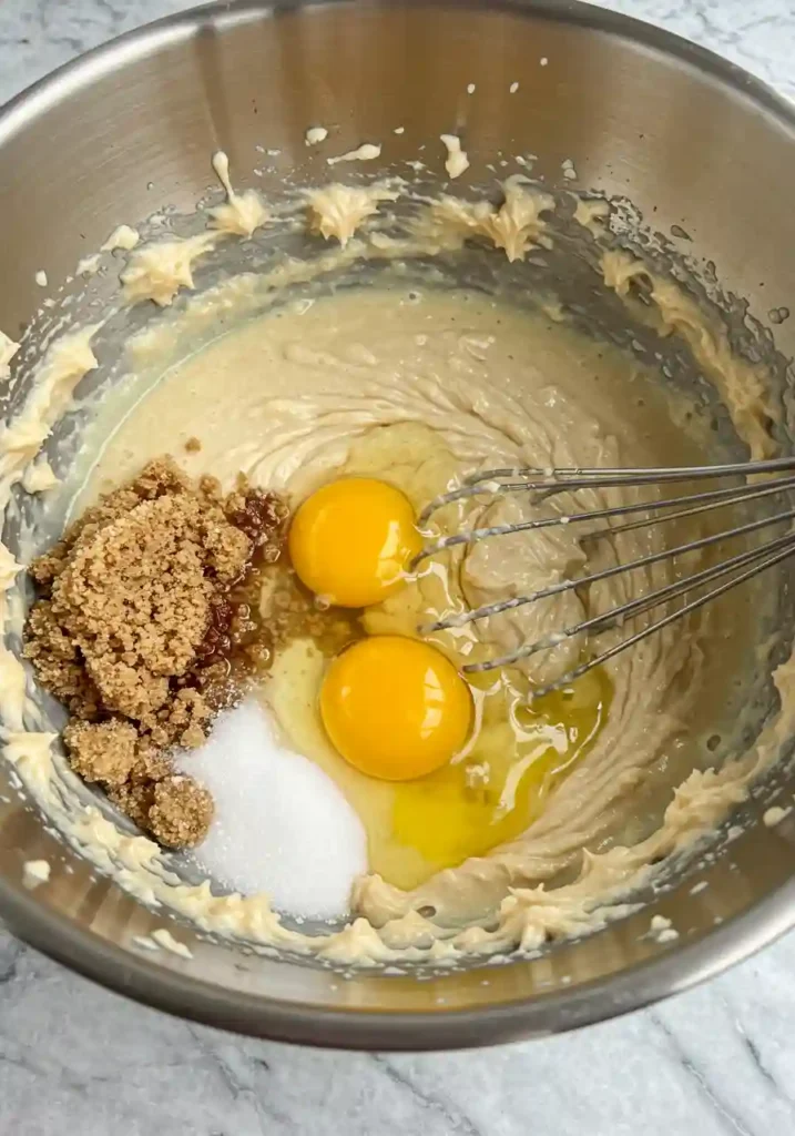 Adding Eggs to Butter and Sugar Mixture in Mixing Bowl
